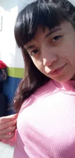 Young woman in pink sweater posing outdoors.