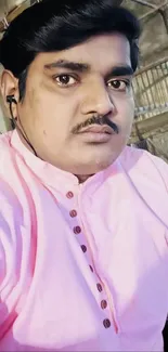 Man in pink shirt with earphones, casual portrait.