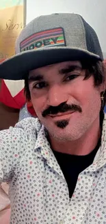 Casual portrait of a person wearing a hat and patterned shirt indoors.