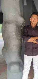 Young man in black shirt standing by a sculpture.