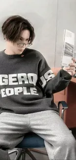 Person in gray sweatshirt reading on chair.