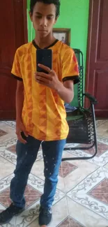 Young individual in geometric orange shirt taking a mirror selfie.