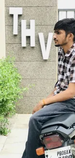 Young man sitting on a motorcycle in an urban setting.