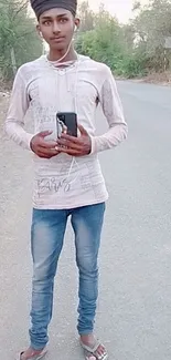 Young man posing on a tranquil country road wearing casual attire.