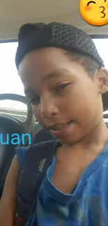 Boy in blue shirt with cap on bus seat, emoji included.