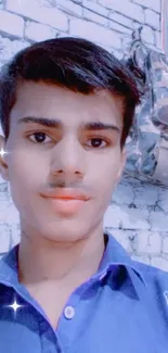 Young person in blue shirt with brick wall backdrop.