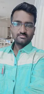 Man in light green shirt with glasses, indoor selfie.