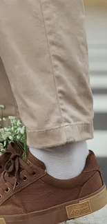 Brown shoe with floral design and beige pants.