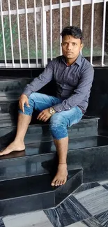 Young man sitting indoors on black steps.