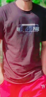 Man in graphic T-shirt and shorts in a natural setting.