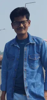 Young person in denim standing on street.