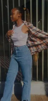 Woman in denim jeans and plaid shirt posing in sunlight.