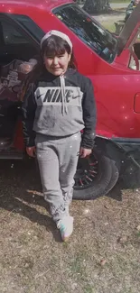 Stylish girl in sporty outfit next to a red car.