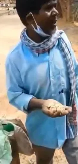 Street vendor in blue shirt, scarf holding items.