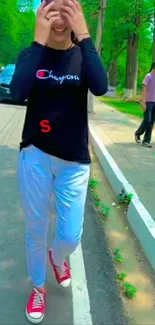 Person walking on a tree-lined street in a casual outfit.