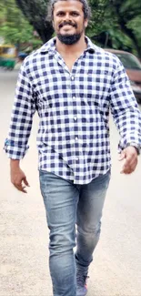 Man in a checkered shirt walking outdoors.