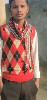 Young man in argyle sweater and plaid scarf outdoors.