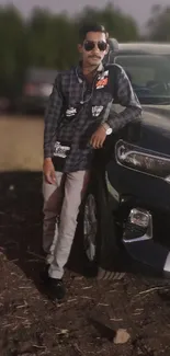 Man in casual outfit leaning on a black car.