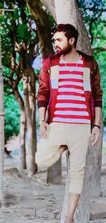 Man in striped shirt relaxes by trees in an urban nature setting.