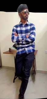 Casual style man in plaid shirt and jeans, posing indoors.