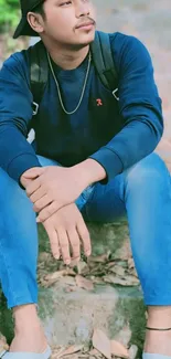 Young man in casual attire sitting on stone steps.