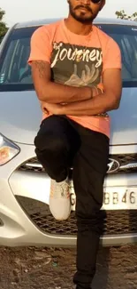 Man in vibrant t-shirt leaning on car, casual outdoor style.