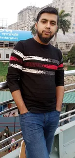 Young man in casual outfit with city backdrop.