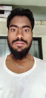 Casual portrait of a bearded man indoors wearing a white shirt.