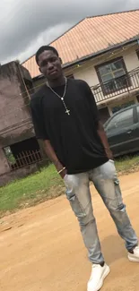 Man in casual black shirt and jeans standing outdoors.