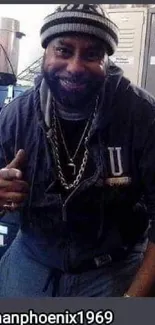 Man dressed casually with chains in a locker room setting.