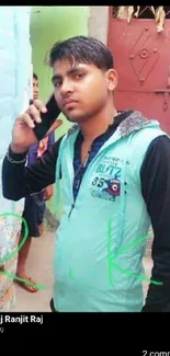 A young man in casual attire on the phone, standing outdoors.