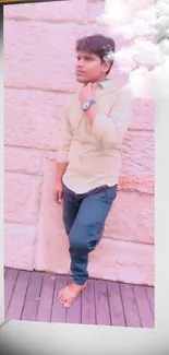 Young man in casual attire against peach wall background.