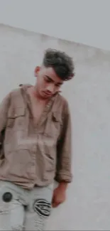 Young man in casual clothes leaning against a wall.