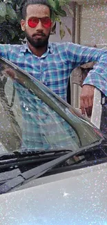 Man in sunglasses leaning on car in urban setting.