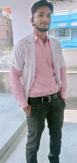 Man in pink shirt and jeans in urban setting with blue background.