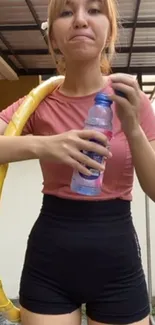 Young woman in workout attire holding water bottle.