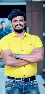 Man in a bright yellow shirt standing confidently indoors.