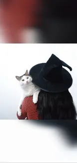 Woman with witch hat holding a cat.