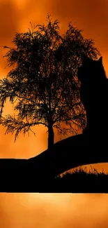 Silhouette of cat and tree against an orange sunset.