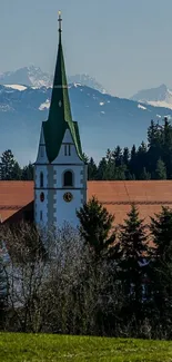 Alpine church with mountain backdrop and blue sky landscape.