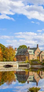 Autumn scene with mansion and lake reflection under a blue, cloudy sky.