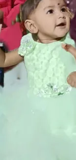 Baby in a pastel green dress, smiling adorably.