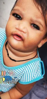 Adorable baby with blue-striped shirt and cute expression for morning greeting.