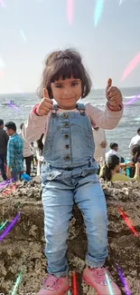 Happy child on beach wall with ocean backdrop.