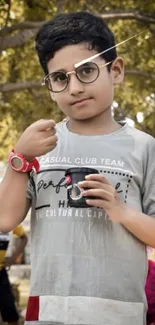 Young boy in glasses standing in an outdoor park.