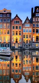 Beautiful Amsterdam canal houses at dusk with reflections in water.