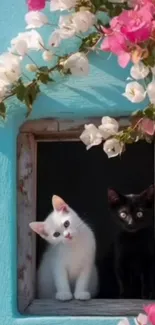 Two cats peering from a flowered window frame.