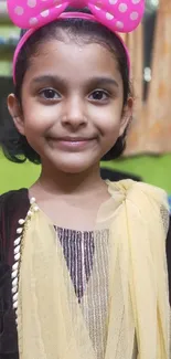 Portrait of a smiling child with a pink bow in colorful background.