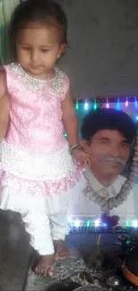 Little girl in pink dress next to LED-lit portrait.