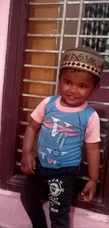 Smiling child in colorful clothes by a window.